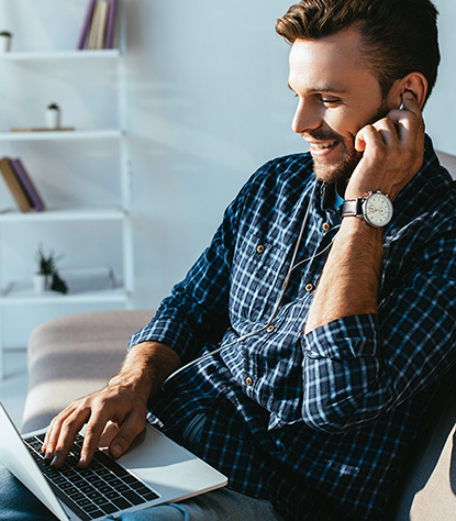 side view of smiling man in earphones taking part in webinar at home